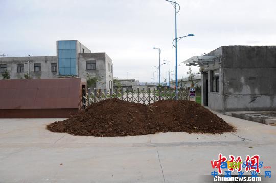 图为厂区门口已被沙土堵路。 记者 张远 摄 图为厂区门口已被沙土堵路。 记者 张远 摄